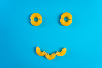 Noodles in a wooden spoon on a blue surface and a chopping board with happy and sad expressions