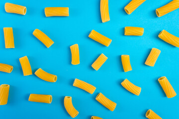 Noodles in a wooden spoon on a blue surface and a chopping board with happy and sad expressions