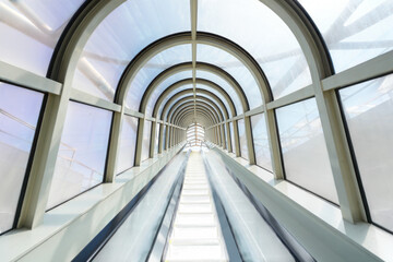 Fototapeta premium Modern architectural tunnel with an upward moving escalator and blue tinted glass panels isolated on transparent background
