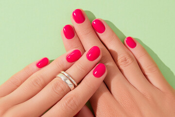 Close up beautiful womans hands with pink nail design on green background. Manicure, pedicure beauty salon concept