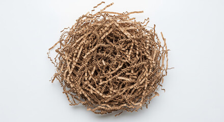 Obraz premium Natural brown zigzag paper shreds for sustainable gift wrapping and parcel protection, scattered in a nest-like form over clean white surface