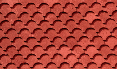 Facade of a house covered with red fish tail ornamental tiles texture.
