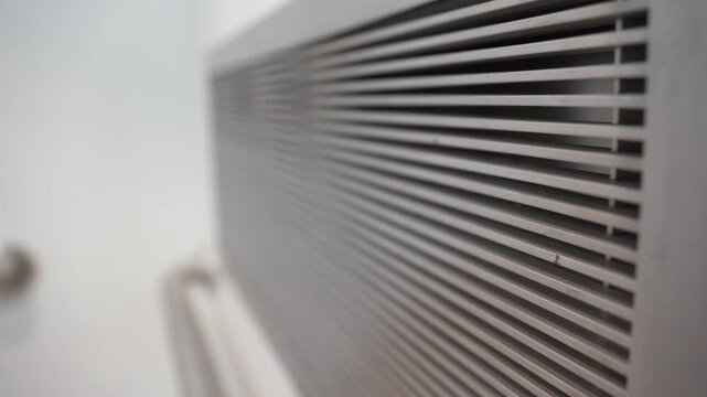 Close-Up of a metal ventilation grille indoors. Part of an air conditioning or ventilation system mounted on the wall.