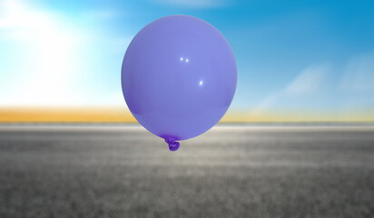 A single purple balloon floats against a bright blue sky with a blurred landscape below.