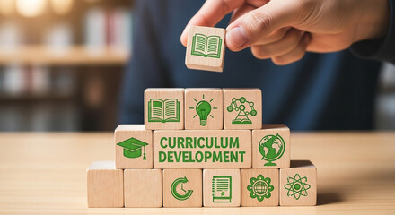 Hand placing a curriculum development block on a stack of wooden blocks with education icons on them