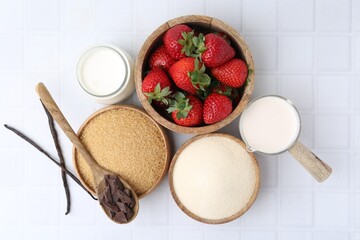Different ingredients for panna cotta. Milk, sugar, vanilla, chocolate and strawberries on white tiled table, flat lay