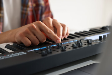 Fototapeta premium Man working with MIDI keyboard at table indoors, closeup