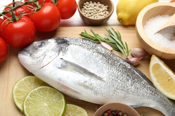 Fresh raw dourade with spices on white wooden table, closeup. Fish and seafood delicacies