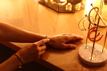 Woman wearing beautiful bracelet while getting ready at dressing table indoors, closeup