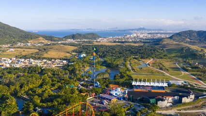 Aerial photo of Beto Carrero World with rides, forest, and city skyline in the background.
