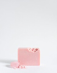 Luxurious pink soap bar with crushed powder and smooth rose quartz crystal on white background