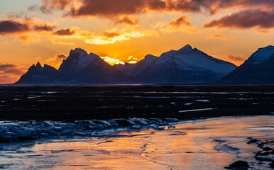 Outdoor scene depicting an icy river against a backdrop of snowy mountains along iceland's south coast in winter.