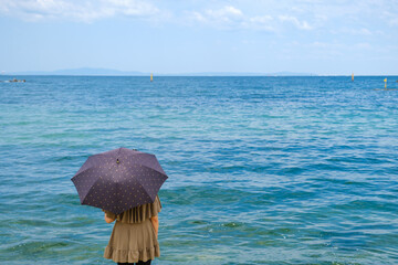 日傘をさして海を眺める女性