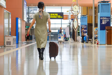 空港で手荷物を押して歩く女性の後姿　旅行客　観光客