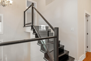 Staircase with a glass railing and a black banister