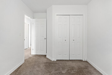 White bedroom with a white closet and a white door