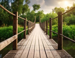 Obraz premium A wooden suspension bridge stretches across a river, leading to a lush green forest under a bright sky.