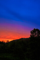 Dramatic sunset over the Green Mountains in Rutland, Vermont, USA, with blazing red and orange clouds lighting up the sky after a refreshing summer rain.