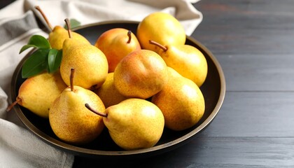 Fresh pears in a dark bowl on a dark wooden surface