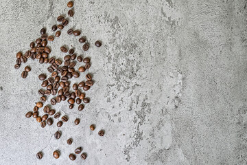 Top view of roasted coffee beans scattered on grey or gray cement as background. high angle, above. copy space, empty free, negative, text, design.