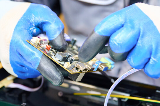 PCB assembly process in electronics manufacturing with technician using gloves and tools
