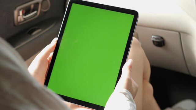 Person is holding a tablet with a green screen. The tablet is in a car
