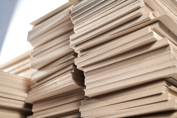 Stacks of thick paperboard awaiting transformation into durable cardboard boxes at a manufacturing facility