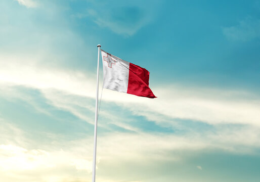Malta flag is waving on a tall flagpole among the clouds. Malta national flag for independence day.