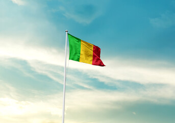 Mali flag is waving on a tall flagpole among the clouds. Mali national flag for independence day.