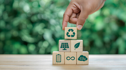 Hand stacking wooden blocks with ecology icons illustrating a sustainable future and environmental responsibility for a greener world