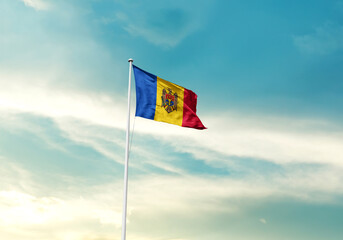Moldova flag is waving on a tall flagpole among the clouds. Moldova national flag for independence day.