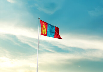 Mongolia flag is waving on a tall flagpole among the clouds. Mongolia national flag for independence day.