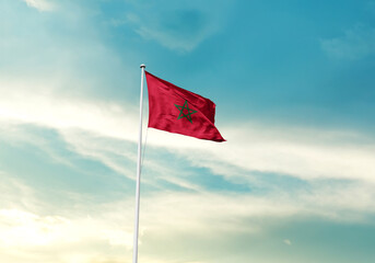 Morocco flag is waving on a tall flagpole among the clouds. Morocco national flag for independence day.