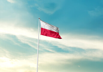 Poland flag is waving on a tall flagpole among the clouds. Poland national flag for independence day.