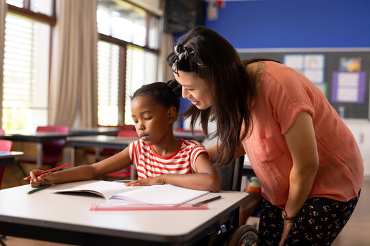 African American girl studies with her teacher in a school classroom