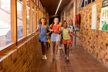 Diverse group of children running in a school hallway