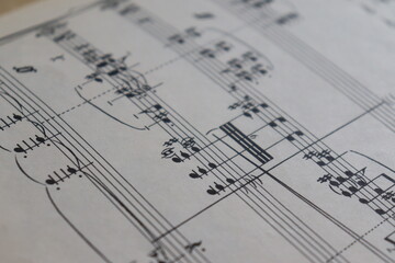 A sheet with a musical partition. Musical notes on a sheet of music paper. Music notes as background with a close-up view.	