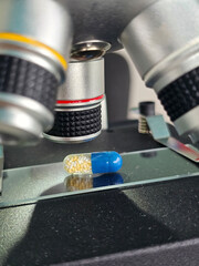 Closeup view of a blue and yellow capsule a microscope lens in a lab setting showcasing scientific exploration