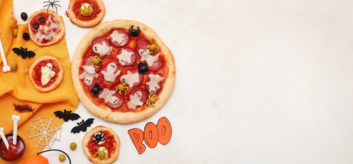 Tasty Halloween pizzas and decorations on light background with space for text