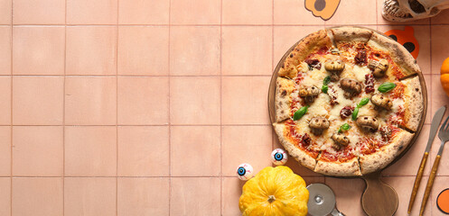 Wooden board of tasty pizza with mushrooms, eyes and pumpkins for Halloween celebration on beige tile background