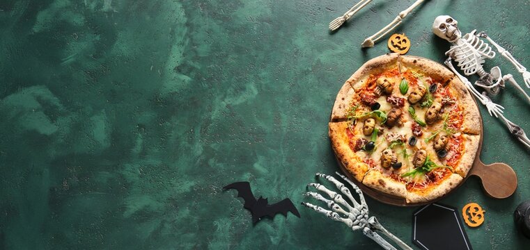 Tasty Halloween pizza and decorations on green background with space for text