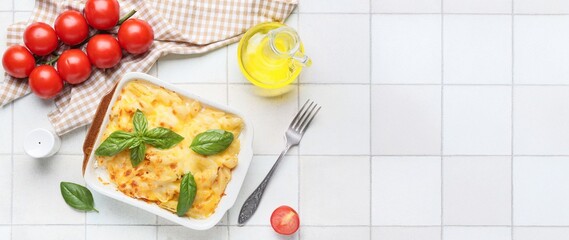Baking dish of tasty pasta with cheese on light tile background with space for text