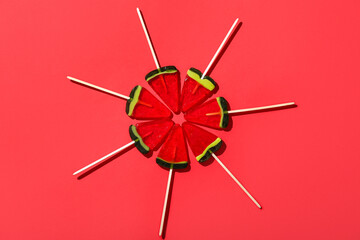 Lollipops in shape of watermelon slice on red background