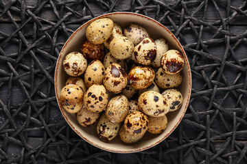 Place mat and bowl with quail eggs on black wooden background