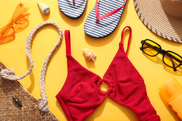 Swimsuit and beach accessories on yellow background