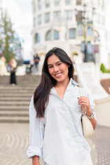 Fototapeta premium Young Asian woman tourist with long black hair in European style town in portrait travel style