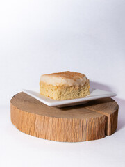 tres leches sponge cake slice on a wooden board on a white background