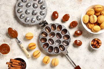 Tasty walnut shaped cookies with boiled condensed milk and baking form on white grunge table