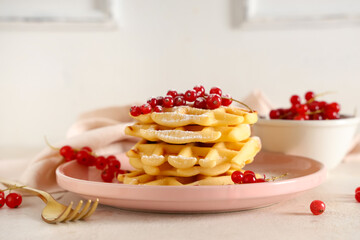 Delicious Belgian waffles with redcurrant and powdered sugar on plate on table against white background