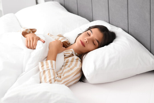Young beautiful woman sleeping and smiling in bed at home